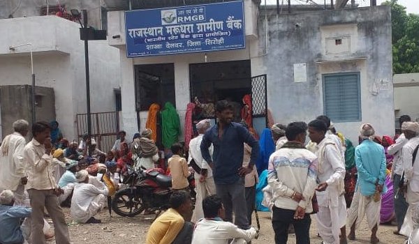 बैंक के गेट पर निराश बैठे आदिवासी।